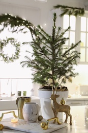 Small decorated Christmas tree and reindeer figure on table in kitchen
