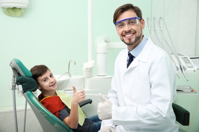 Professional dentist and happy little patient in modern clinic