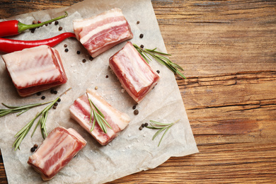 Photo of Raw ribs with rosemary and spices on wooden table, flat lay