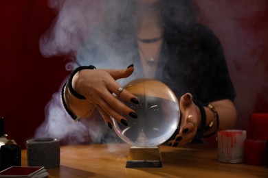 Soothsayer using crystal ball to predict future at table indoors, closeup