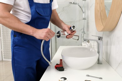 Professional plumber fixing water tap in bathroom, closeup