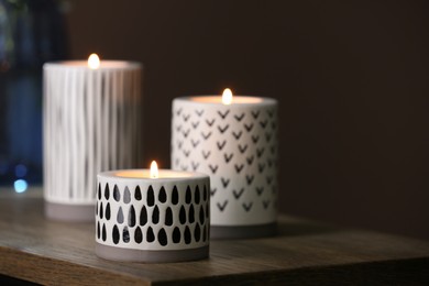 Photo of Different burning candles on wooden table, closeup view. Space for text
