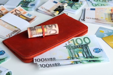 Wallet, different Euro banknotes and credit cards on white table, closeup. Money exchange