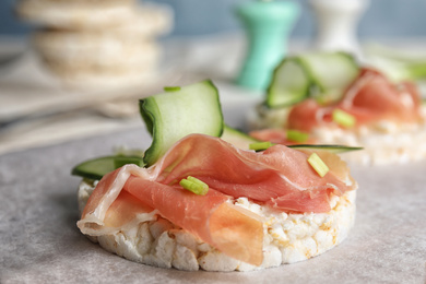 Puffed rice cake with prosciutto and cucumber on parchment paper, closeup