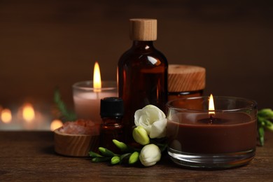 Photo of Beautiful spa composition with burning candles, different care products and flowers on wooden table