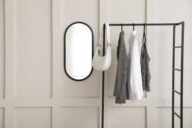 Simple hallway interior with clothing rack and mirror on light textured wall