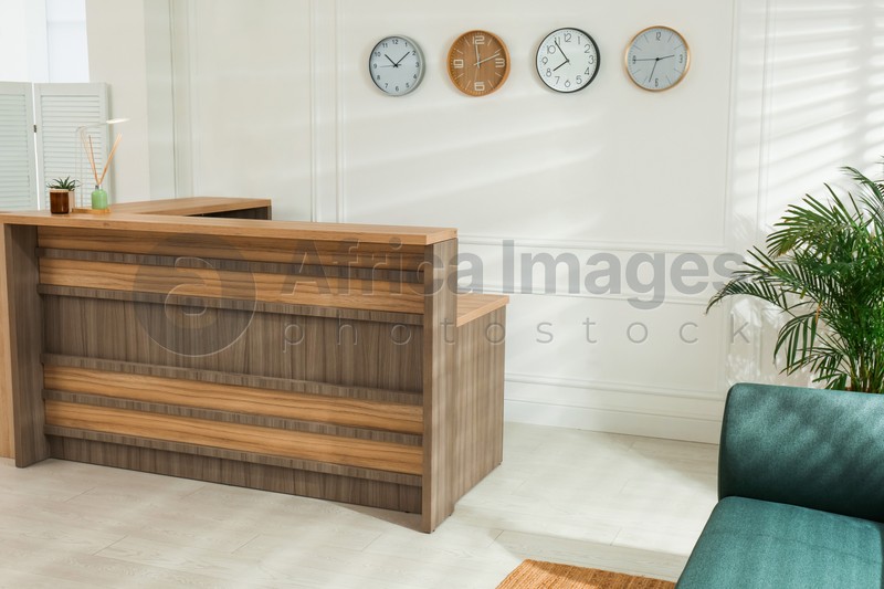 Photo of Hotel lobby interior with wooden reception desk. Stylish workplace