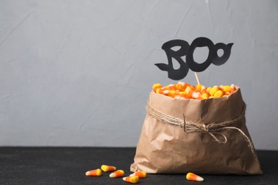 Paper bag with tasty candy corns on table against gray background. Space for text