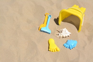 Bright plastic bucket and rakes on sand. Beach toys. Space for text