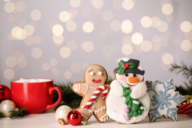 Sweet Christmas cookies and decor on white table against blurred festive lights