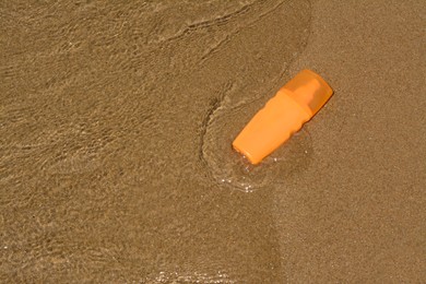 Photo of Bottle with sun protection spray near sea, above view. Space for text