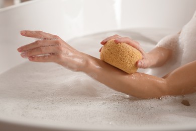 Woman rubbing her forearm with sponge while taking bath, closeup