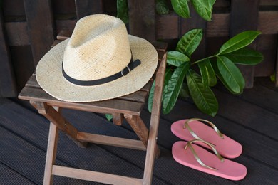 Stylish hat and flip flops near wooden fence. Beach accessories