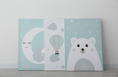 Different adorable pictures on floor near white wall. Children's room interior elements