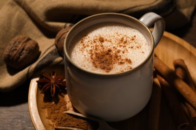 Photo of Cup of delicious eggnog with spices on wooden table