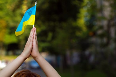 Photo of Boy holding Ukrainian flag against blurred background, closeup. Space for text