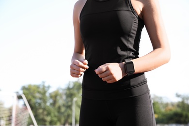Woman with fitness tracker running outdoors, closeup
