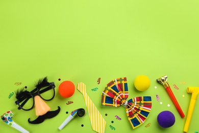 Flat lay composition with clown's accessories on green background. Space for text