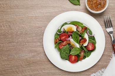 Photo of Delicious salad with boiled egg, bacon and vegetables served on wooden table, flat lay. Space for text