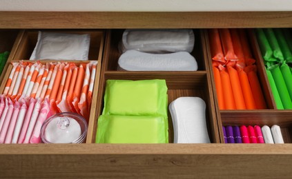 Storage of different feminine hygiene products in wooden drawer, closeup