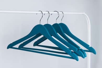 Blue clothes hangers on metal rack against light background