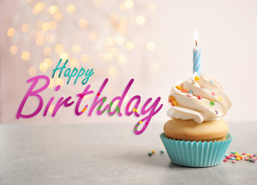 Text Happy Birthday and delicious cupcake with candle on blurred background