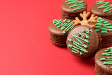 Beautifully decorated Christmas macarons on red background, closeup. Space for text