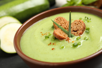 Tasty homemade zucchini cream soup in bowl on table, closeup