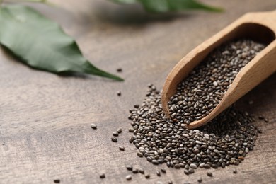 Photo of Scoop with chia seeds on wooden table, closeup. Space for text