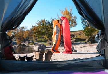 Cute couple in sleeping bags outdoors, view from camping tent