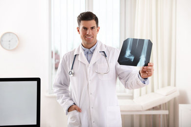 Professional orthopedist examining X-ray picture in clinic