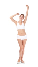 Photo of Happy young woman satisfied with her diet results using bathroom scales on white background