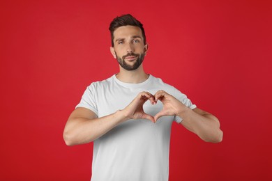 Man making heart with hands on red background