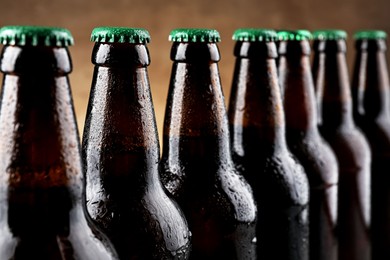Photo of Many bottles of beer on light brown background, closeup