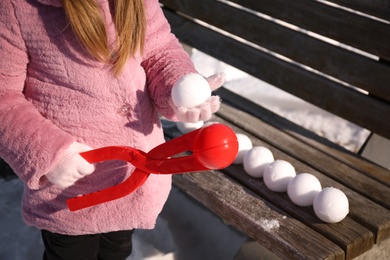 Little girl playing with snowball maker outdoors, closeup