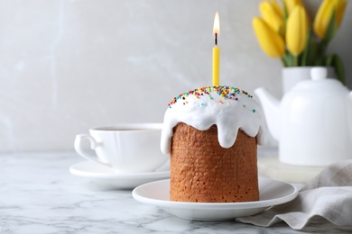 Beautiful Easter cake with candle on white marble table. Space for text