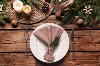 Photo of Festive place setting with beautiful dishware, cutlery and fabric napkin for Christmas dinner on wooden table, flat lay