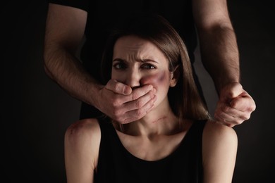 Man abusing scared woman on black background. Domestic violence