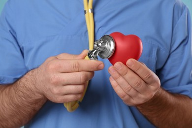 Doctor with stethoscope and red heart, closeup. Cardiology concept
