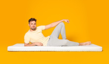 Photo of Man lying on soft mattress against orange background