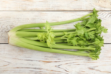 Photo of Fresh ripe green celery on white wooden table, top view