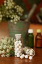 Bottles with homeopathic remedy and flowers on table
