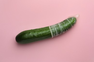 Cucumber with condom on pink background, top view. Safe sex concept