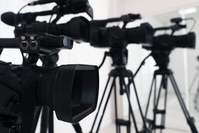 Photo of Modern video camera indoors, focus on lens. Professional media equipment for broadcasting event