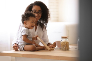 African-American woman with her baby in kitchen. Happiness of motherhood