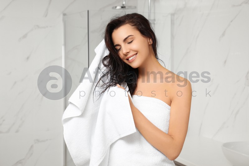 Young woman drying hair with towel in bathroom