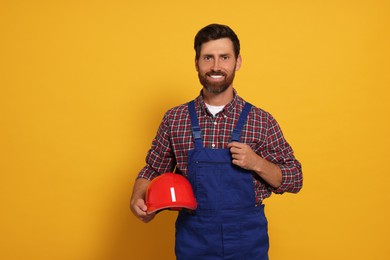 Professional builder with hard hat on yellow background