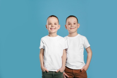 Portrait of cute twin brothers on color background