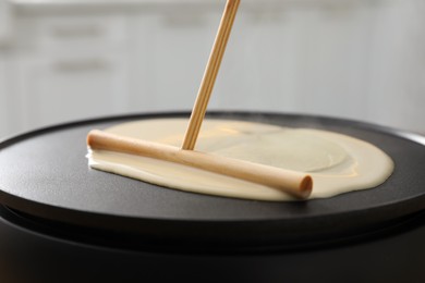 Cooking delicious crepe on electrical pancake maker, closeup