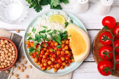 Delicious chickpea curry with rice served on white wooden table, flat lay